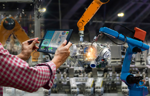 Worker holding tablet with machines working nearby