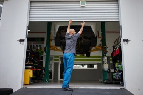 Mechanic opening garage door to car shop