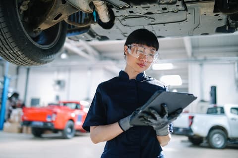 Mechanic holding tablet in car repair shop