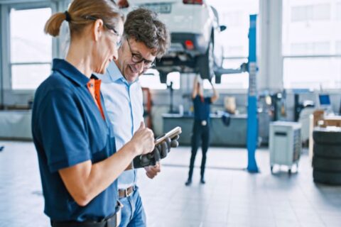 Manager and mechanic coordinate using mobile phone at workshop